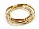 a close up of three gold rings on a white surface