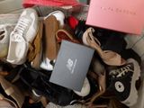 many pairs of shoes in a box on a bed
