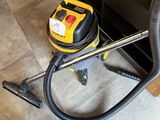 un aspirateur jaune et noir posé par terre à côté d'un meuble noir