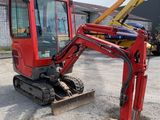a red excavator parked in a parking lot next to a building
