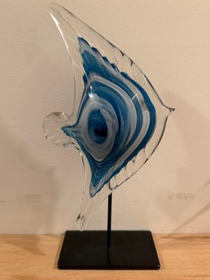a glass sculpture of a fish on a black stand