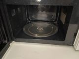a black microwave with a metal pan inside of it
