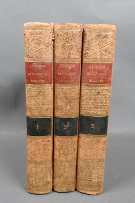 three old books sitting on top of each other on a gray surface