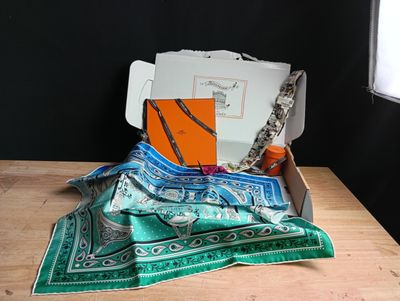 a box that has a scarf and other items in it on a table