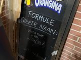 a chalk board with a menu written on it in front of a brick wall