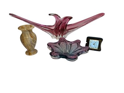 a glass sculpture of a bird and a clock on a table