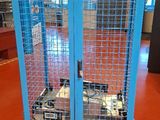 a large blue metal cage with two wheels on the floor