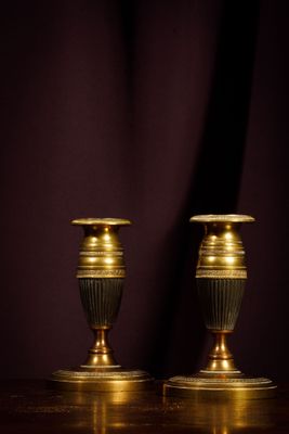 pair of antique brass candlesticks on a wooden table against a dark background