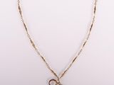 un collier en or avec une pièce et une chaîne sur fond blanc