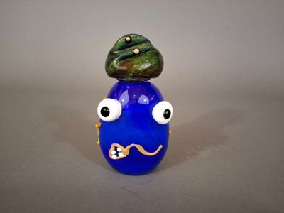 un vase bleu surmonté d'un chapeau vert
