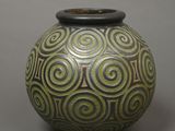 a green and black vase sitting on a gray surface