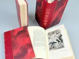 three red books are open on a gray surface