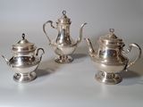 trois théières en argent et une théière en argent posées sur une table