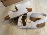 a pair of white sandals on the floor next to a cardboard box