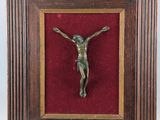 un crucifix en bronze dans un cadre en bois recouvert de velours rouge