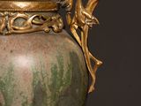 a green vase with a gold handle sitting on a table