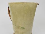 a white pitcher with a brown handle on a white surface