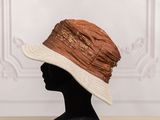 a close up of a mannequin head wearing a brown and white hat