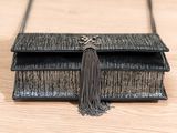 black leather purse with tassel and chain on wooden table