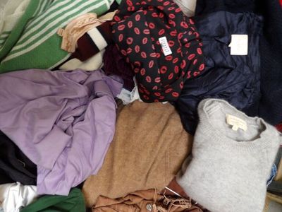 une valise pleine de vêtements et des vêtements par terre