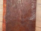 un vieux livre en cuir marron posé sur une table en bois
