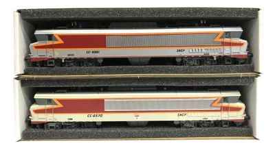 trois trains miniatures sont rangés dans des boîtes posées sur une surface blanche