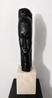 sculpture noire représentant la tête d'une femme, posée sur un socle en marbre