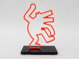 an orange neon sculpture of a man holding a knife on top of a black base