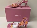 des chaussures à talons hauts roses dans une boîte rose posée sur une surface blanche