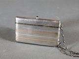 a silver purse with a chain around it on a table