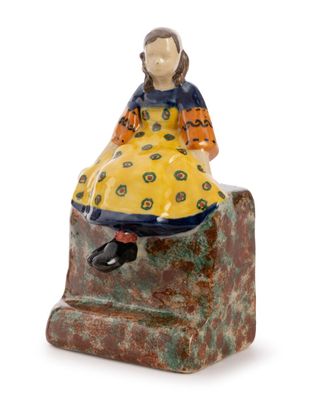a close up of a figurine of a woman sitting on a rock