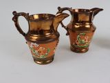 three pieces of copper colored vases sitting next to each other