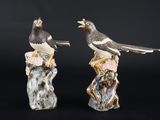 deux figurines d'oiseaux perchés sur une souche d'arbre