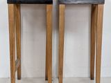pair of wooden stools with black marble tops against a white wall