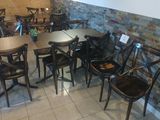 tables and chairs in a restaurant with a brick wall in the background