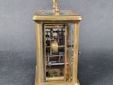 a small gold clock with a pendulum on top of it
