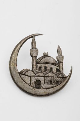 a silver brooch depicting a mosque and a crescent