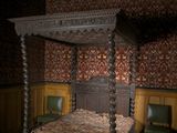 a bed with a canopy in a room with wood paneled walls