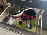 many pots and pans in the drawer of a kitchen