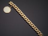 a gold bracelet with a coin on a black background
