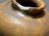 a brown vase with a handle sitting on a table