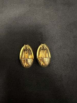a pair of gold earrings with a picture of a woman on it