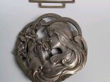 une broche en argent représentant une femme et des fleurs