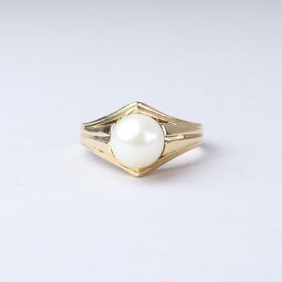 a close up of a gold ring with a pearl in it