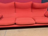 un canapé rouge orné de coussins, devant un mur rouge