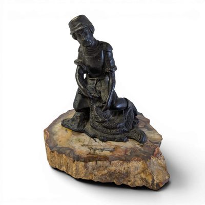 statue of a man kneeling on a rock with a dog