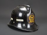an old black fireman ' s helmet with a badge on it