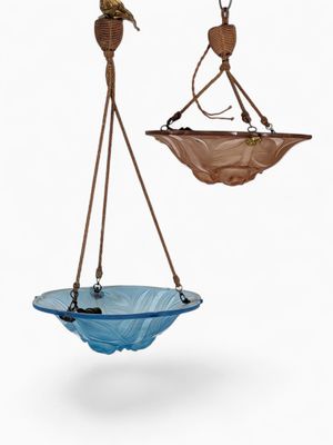 two blue glass bowls hanging from a rope on a white background