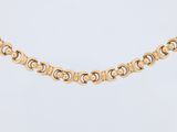 a gold necklace with a circular design on a white background