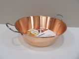 une grande casserole en cuivre avec une poignée et une cuillère